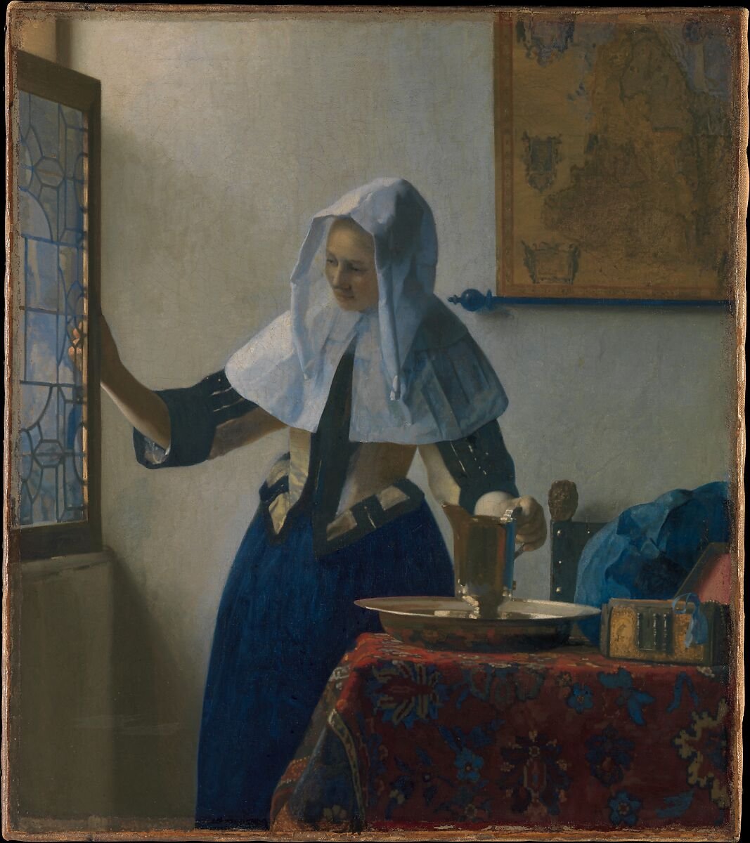 Vermeer's Young Woman with a Water Pitcher: a woman in a white headdress stands between a bright window and a table holding a metal basin and pitcher.