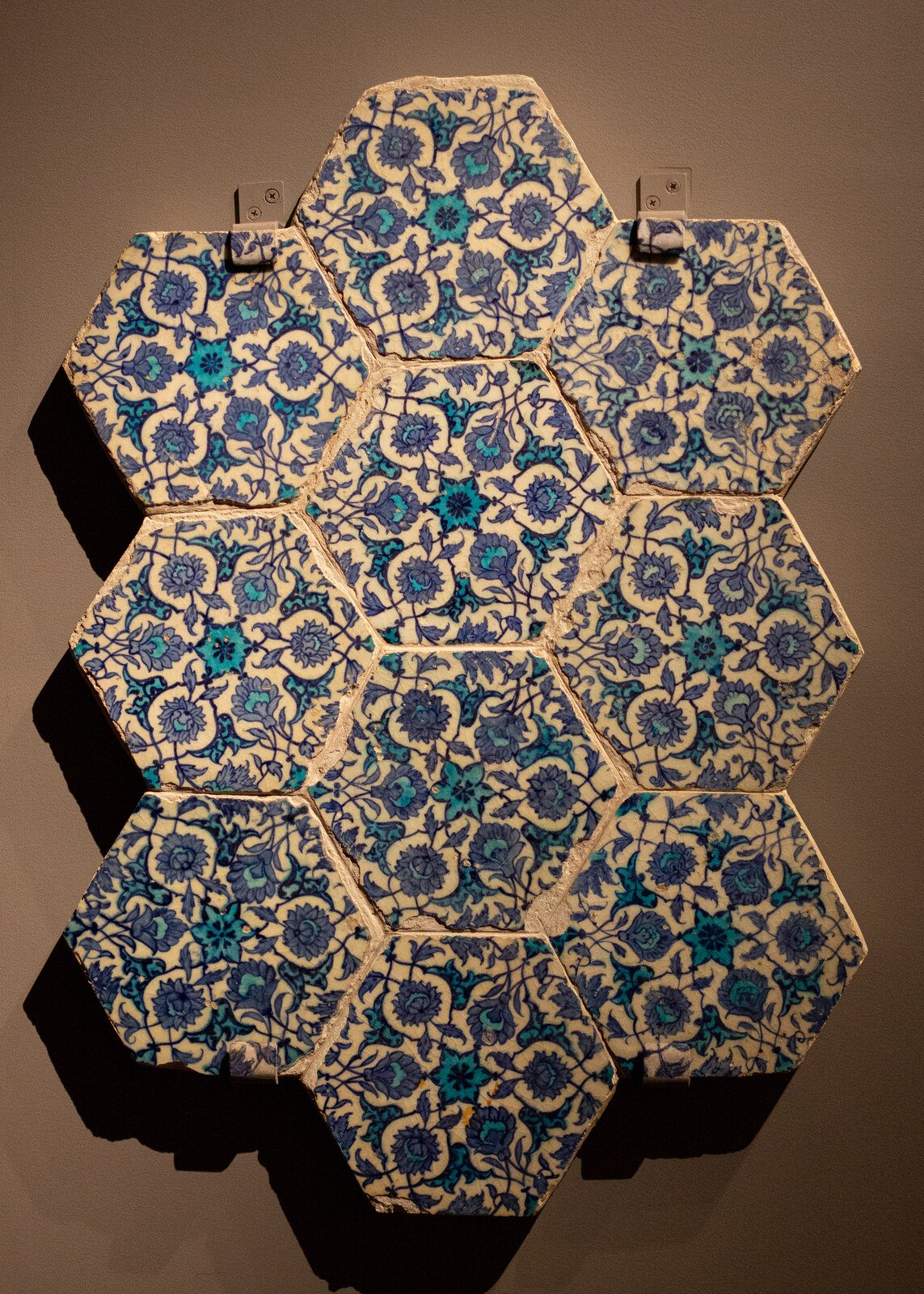 Seven hexagonal ceramic tiles painted in cobalt and turquoise with floral motifs that continue across tile boundaries.